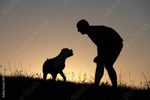 Herrchen und Hund als Silhouette bei Sonnenuntergang