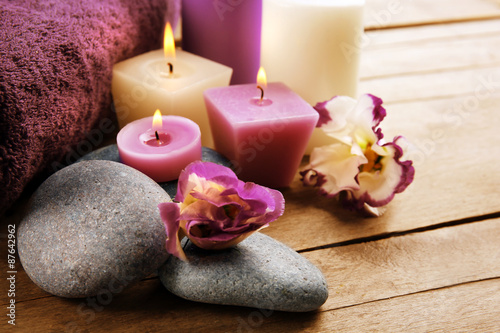 Spa still life with towels  pebbles  purple flowers and candlelight on wooden table  closeup