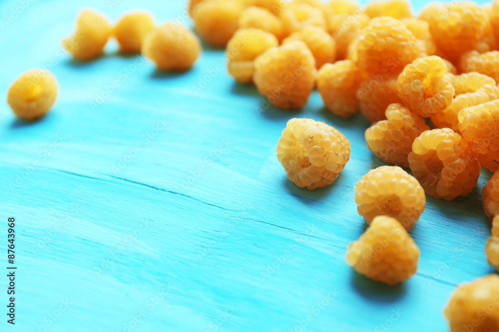 Yellow raspberries on turquoise wooden background Yellow raspberries on turquoise wooden background
