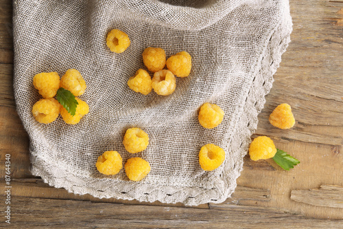 Yellow raspberries on sackcloth on wooden table, closeup