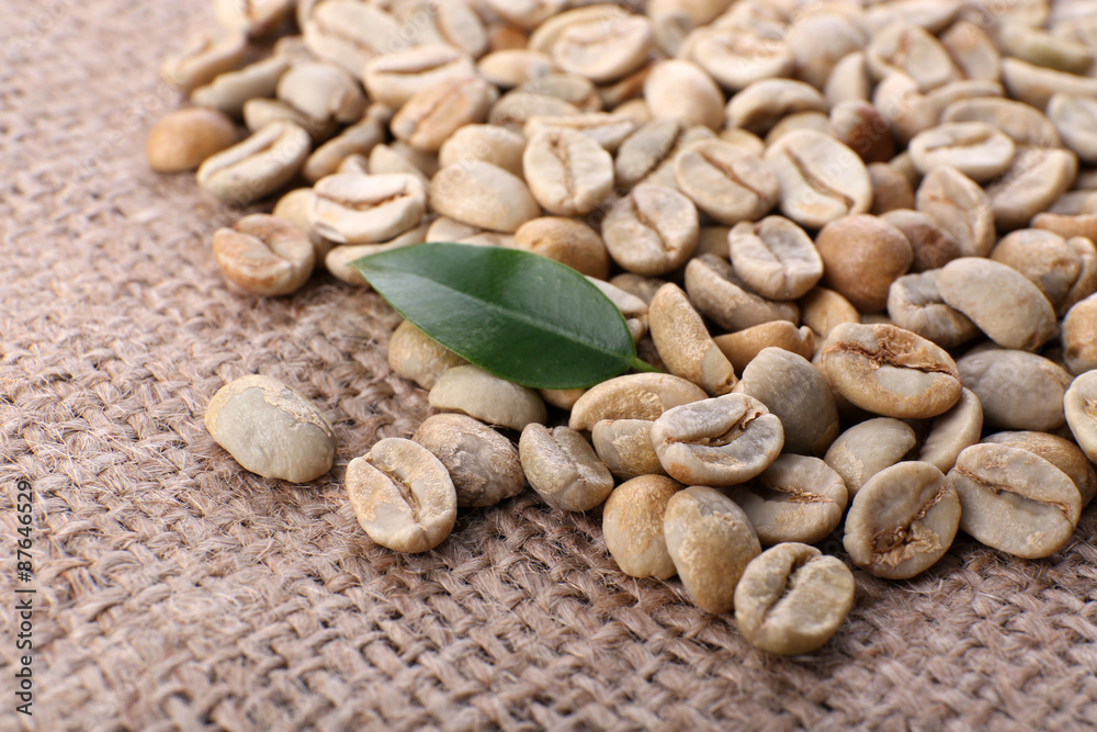 Heap of green coffee beans with leaf on sackcloth close up Heap of green coffee beans with leaf on sackcloth close up