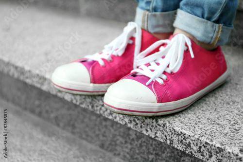 Female feet in pink gumshoes on stone stairs