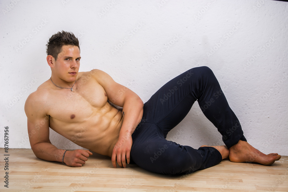 Obraz premium Handsome young bodybuilder laying down on the floor