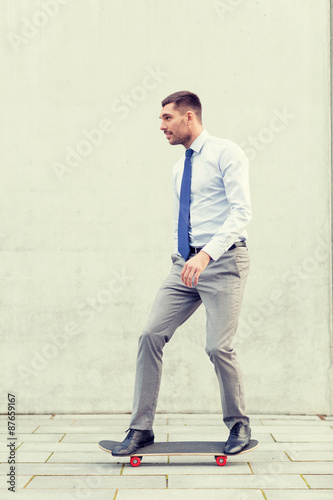 young smiling businessman with skateboard outdoors