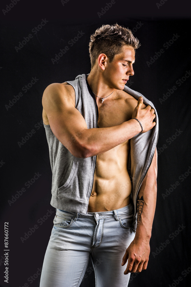 Confident, attractive young man with open vest on muscular torso Confident, attractive young man with open vest on muscular torso