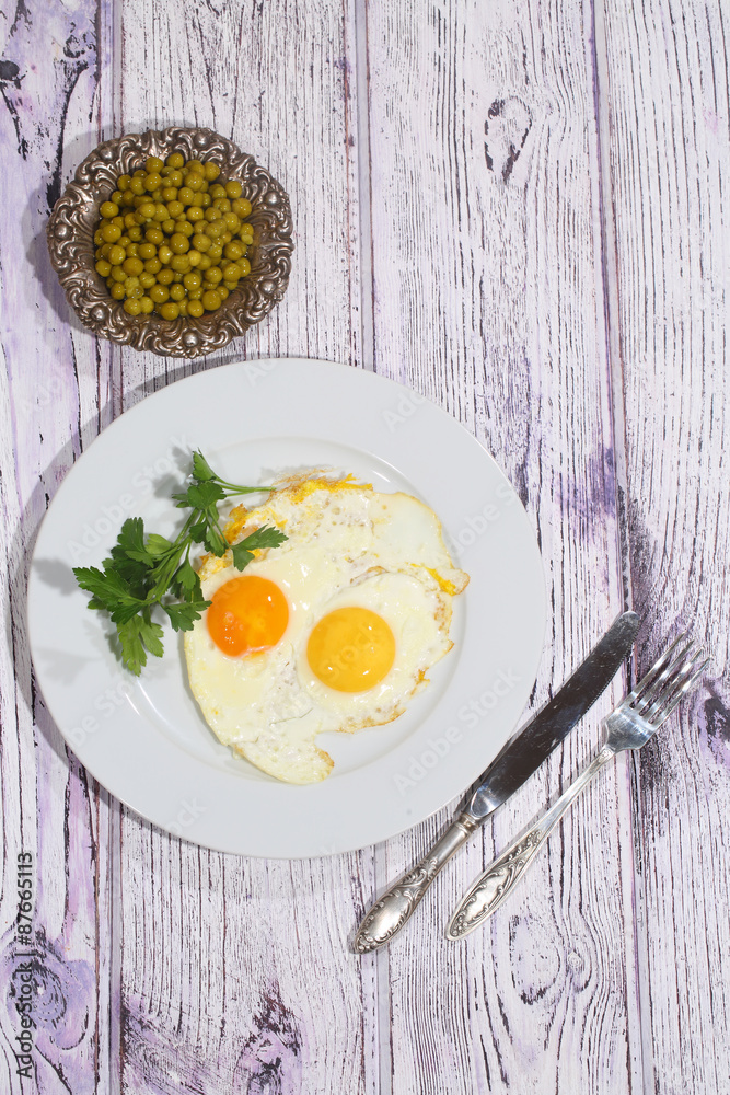 Fried eggs with fresh parsley and a green peas Fried eggs with fresh parsley and a green peas