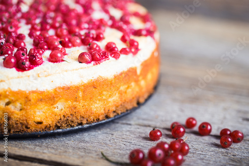 cheesecake with fresh red currants on a thin wooden background