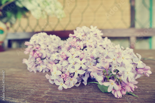 Vintage image of lilac flowers on the rustic wooden table. Photo filtered in faded, washed out, Instagram, retro style. Romantic, nostalgic vintage concept.