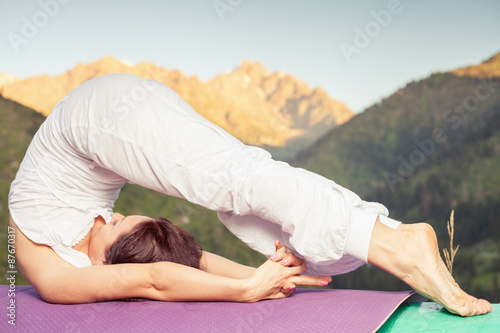 woman doing yoga at mountain