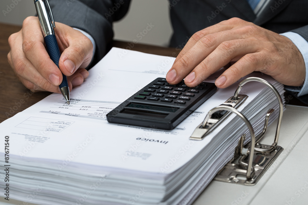 Businessman Calculating Bills In Office