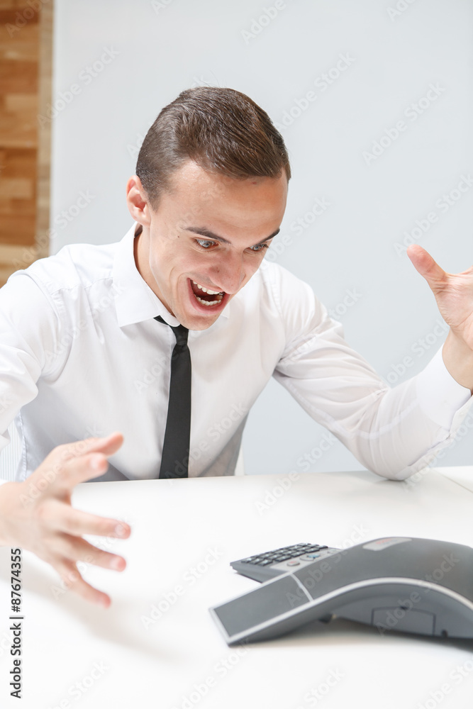 Angry businessman talks on the conference call in the office Angry businessman talks on the conference call in the office