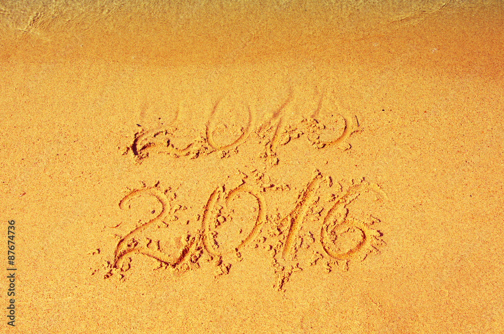 Fototapeta premium 2015 - 2016 on sea sand. 2015 almost washed away a wave. Happy New Year 2016 replace 2015 concept on sea beach . Leaving and coming year