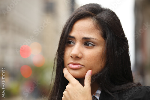 A woman with her hand on her chin as if trying to make a decision.