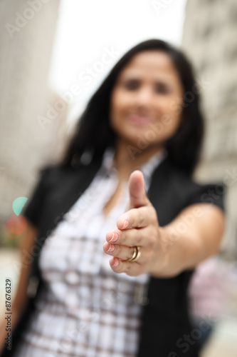 A woman extends her hand for a handshake. Focus is on her hand.