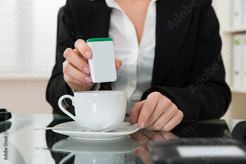 Close-up Of Businesswoman Putting Sugar In Cup