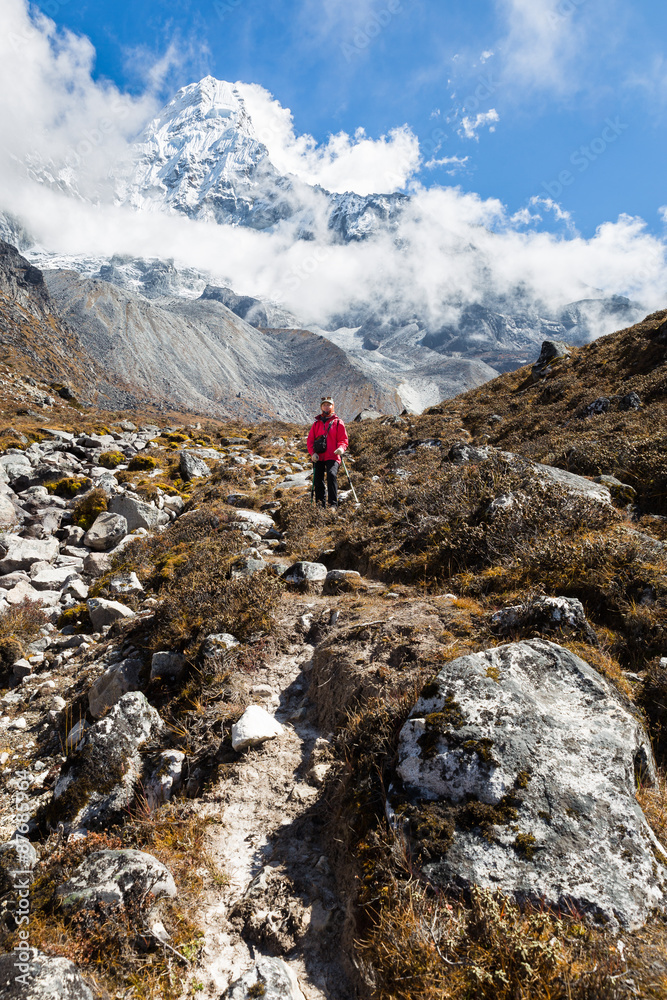 Fototapeta premium Woman backpacker standing in front Ama Dablam mountain. Vertical