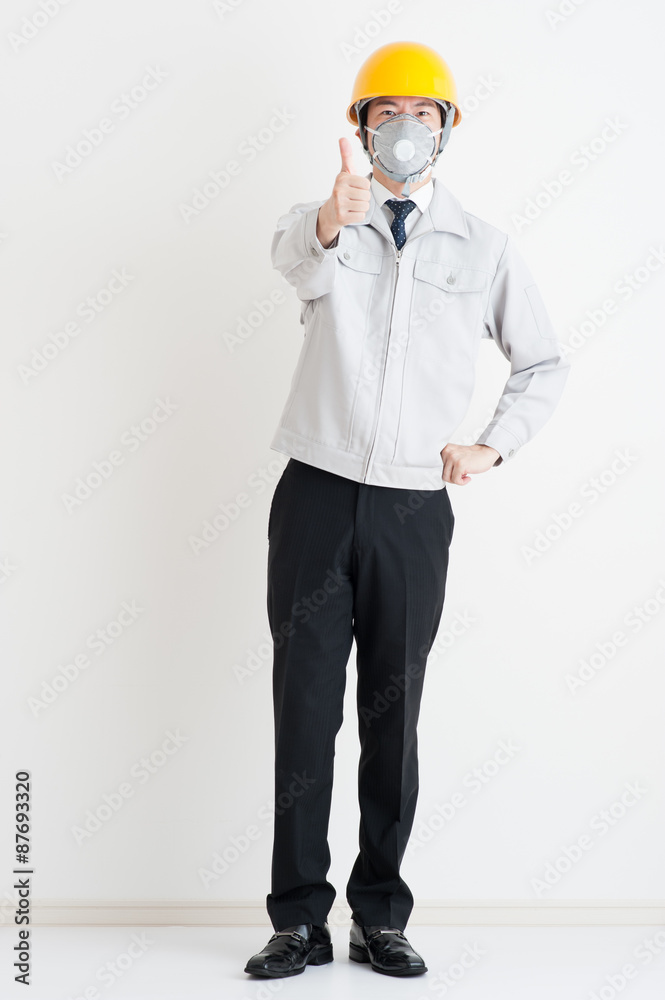 作業服の男性の全身写真,親指を立てている