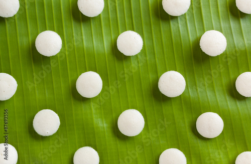 Fresh Indian mini idly - Fresh steamed Indian mini Idly (Idli / rice cake) arranged decoratively on traditional banana leaf. Can also be used as food backgrounds. Natural light used.