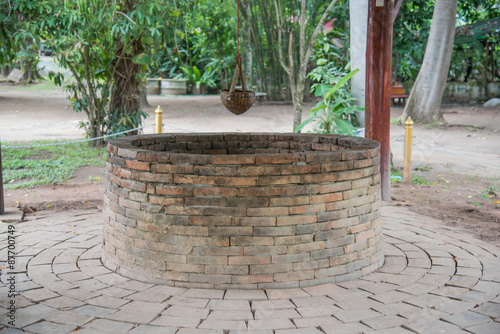 Ancient brick well and Bamboo Basket for dip up water