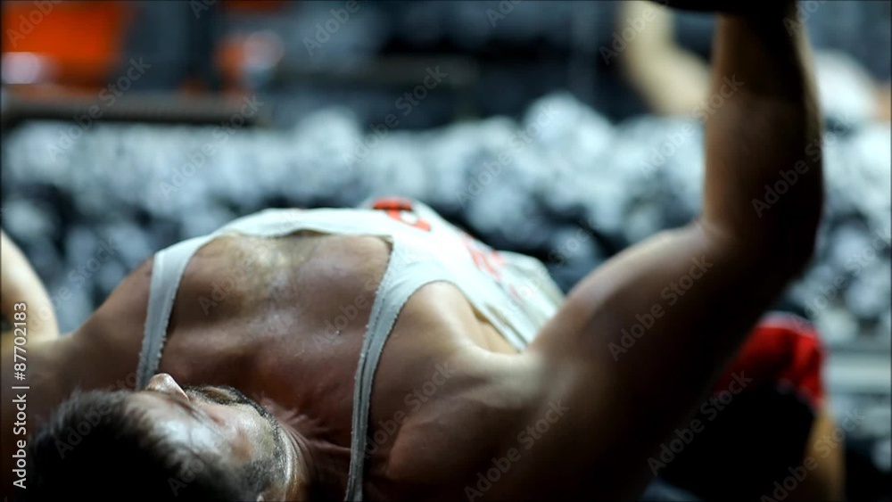 a man in a sports body is engaged in the gym lifting heavy weights with emotional stress. The men in club up the heavy equipment for bodybuilding and he have strong hands. a man in a sports body is engaged in the gym lifting heavy weights with emotional stress. The men in club up the heavy equipment for bodybuilding and he have strong hands.
