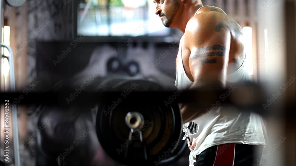 a man in a sports body is engaged in the gym lifting heavy weights with emotional stress. The men in club up the heavy equipment for bodybuilding and he have strong hands. a man in a sports body is engaged in the gym lifting heavy weights with emotional stress. The men in club up the heavy equipment for bodybuilding and he have strong hands.