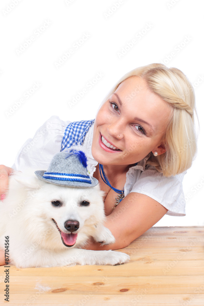 Frau im Dirndl mit niedlichen weißen Spitz mit bayrischem Hütchen Frau im Dirndl mit niedlichen weißen Spitz mit bayrischem Hütchen