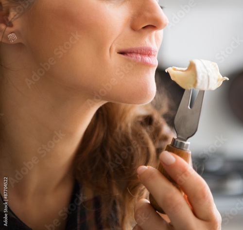 Closeup of woman's mouth getting ready to eat piece of Camembert