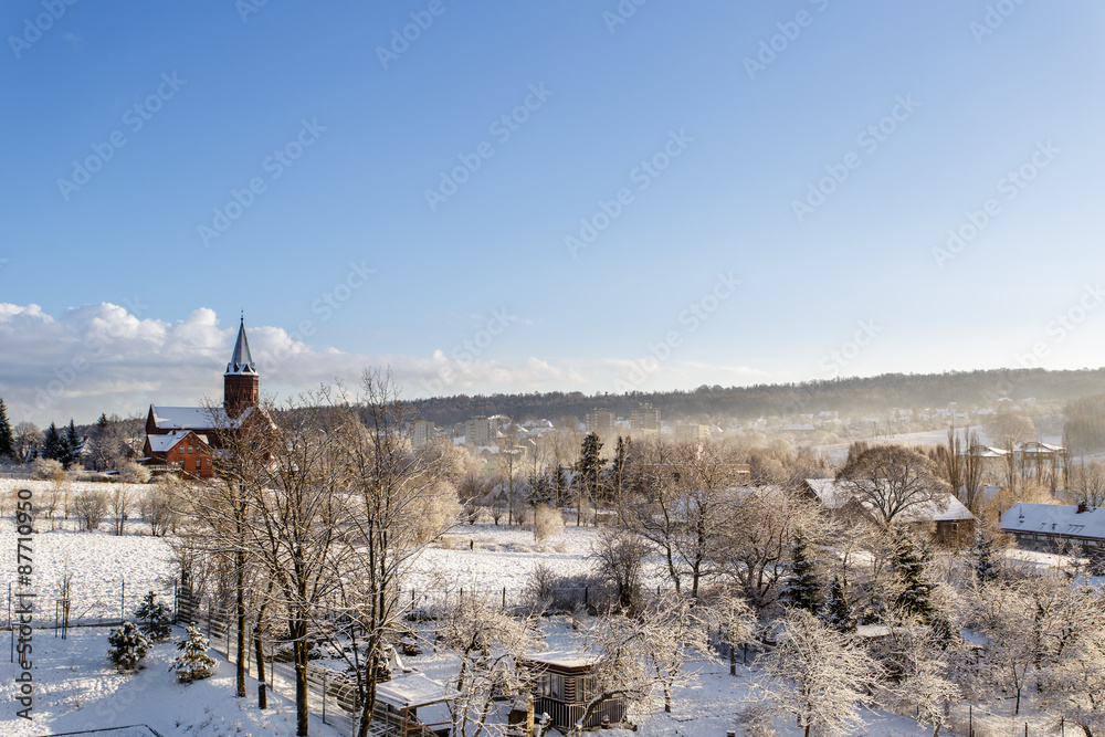 Eine Kirche und teile des dorfes im Winter bei blauem Himmel