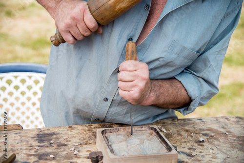 Old woodcarver working with mallet and chiesel, vintage style photo