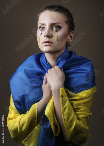 Close-up portrait of a girl with makeup and tears of yellow and blue photo