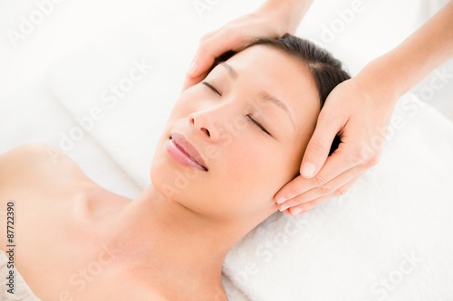 Attractive young woman receiving head massage at spa center