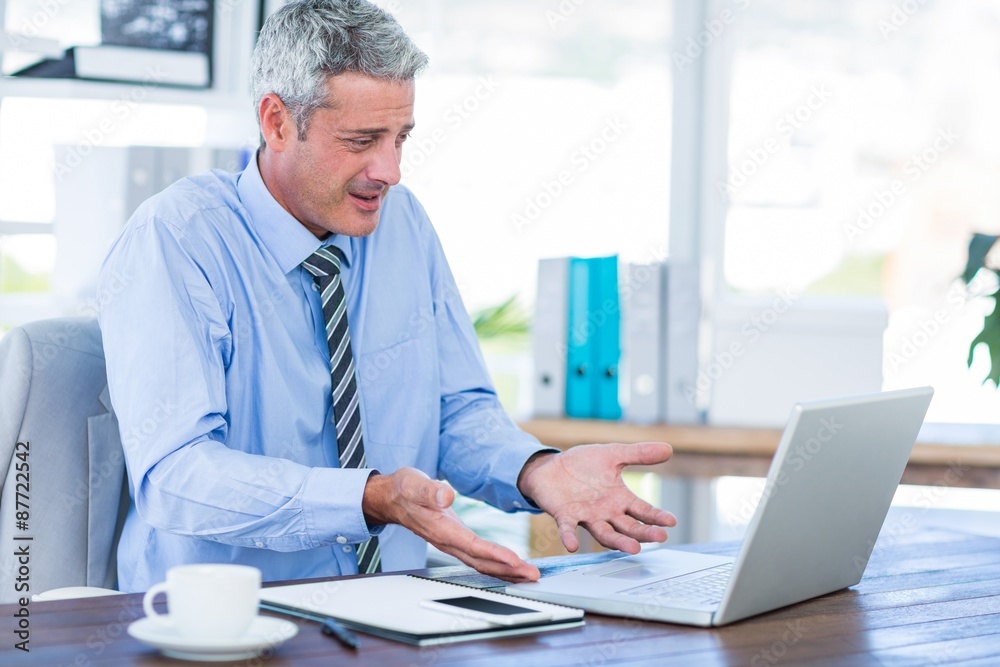 Confused businessman looking at laptop computer 