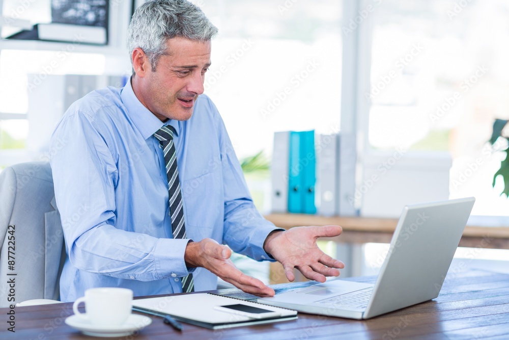 Confused businessman looking at laptop computer Confused businessman looking at laptop computer