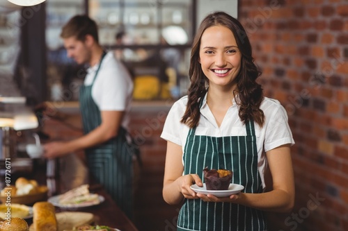 Pretty waitress holding a plate with muffin