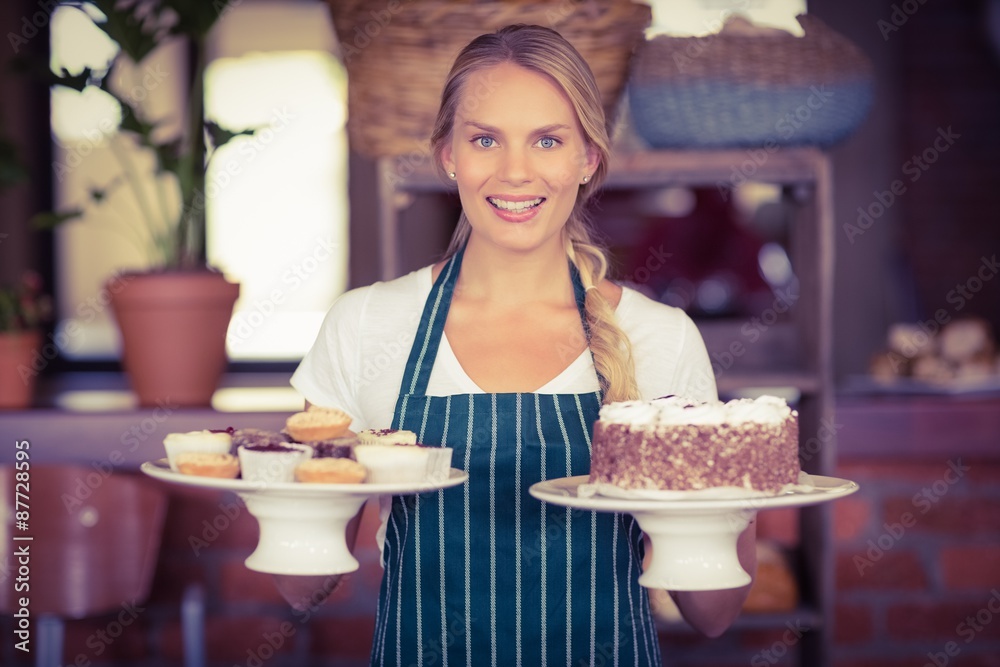 Pretty waitress holding a chocolate cake and cupcakes Pretty waitress holding a chocolate cake and cupcakes