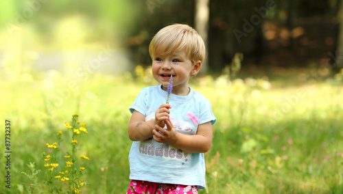 Mała dziewczynka z kwiatkiem na łące.