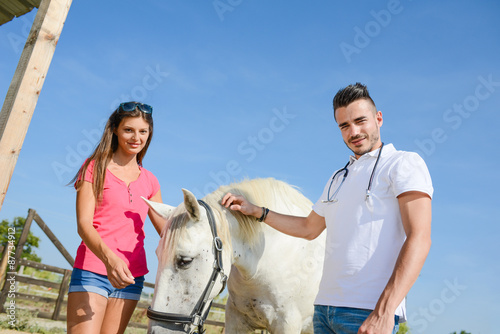 handsome young man veterinary taking care of a beautiful white and gray camargue horse