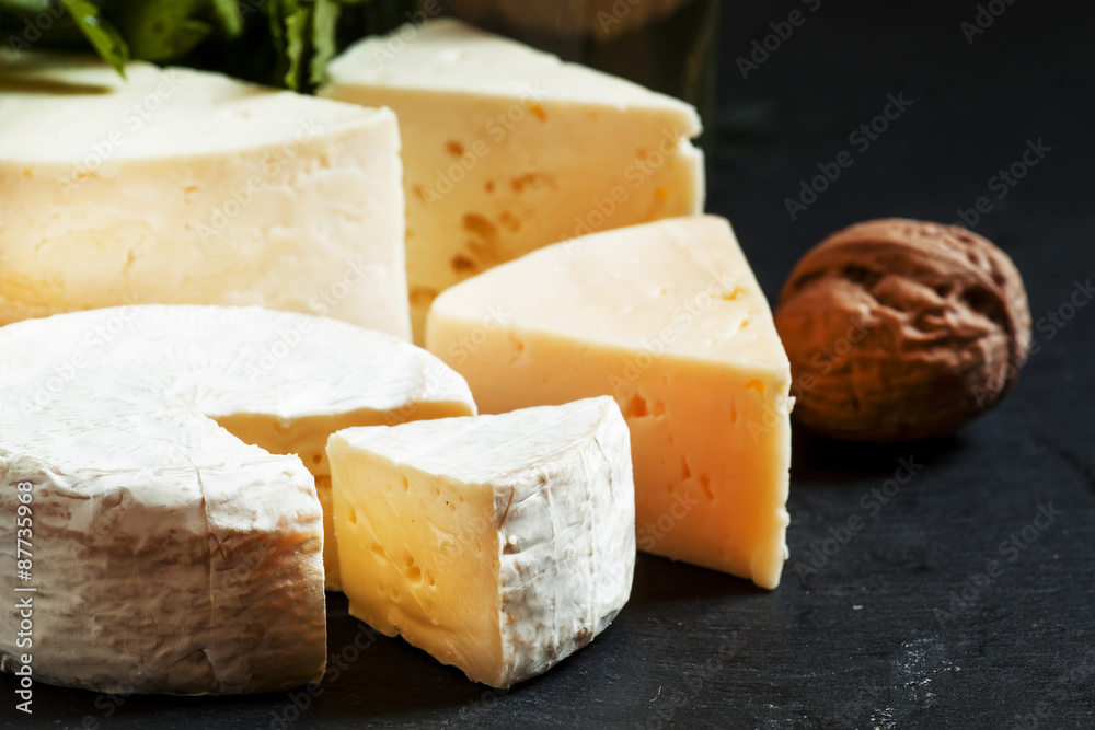 Assorted different kinds of cheese, nuts, herbs, white wine on a