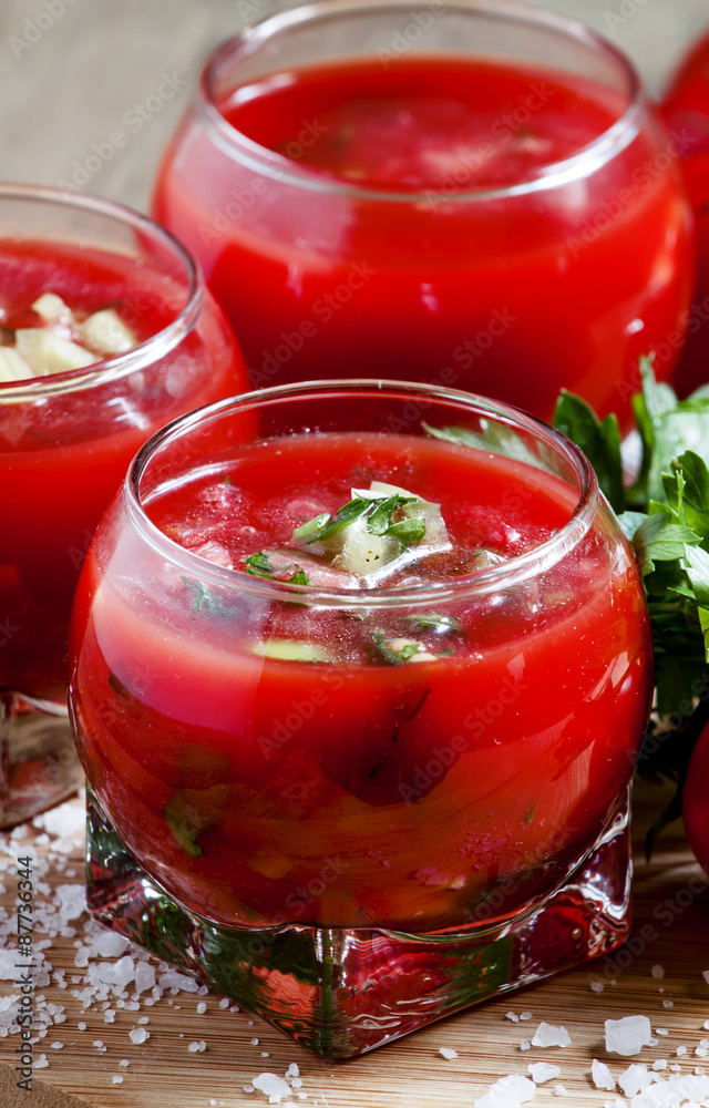 Tomato soup with vegetables in a round glass bowl, selective foc Tomato soup with vegetables in a round glass bowl, selective foc