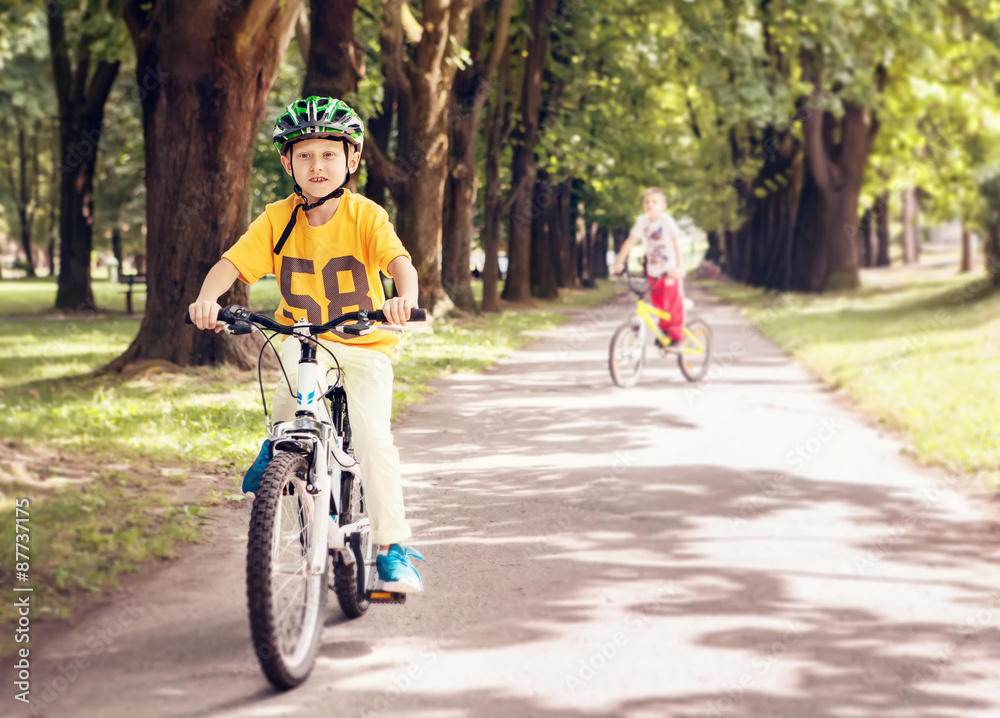 Two boys ride a bicycle in park