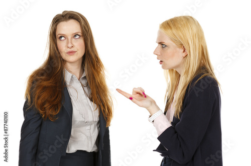 One woman points her finger at another while the other looks away in annoyance.