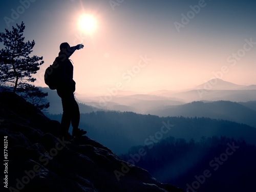 Sunny morning. Hiker is standing on the peak of rock in rock empires park and watch over misty and foggy morning valley