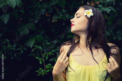 Beautiful young woman standing in the summer rain. Custom white balance used and some color effects are added to this image.