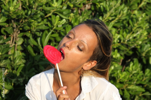 Ragazza mangia lecca lecca a forma di cuore photo