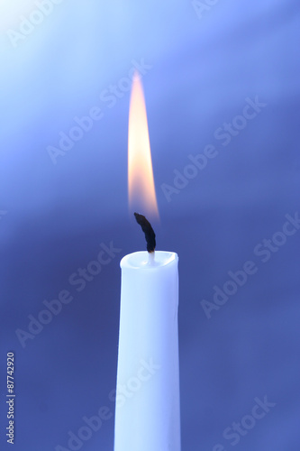 burning white candle on a blue background