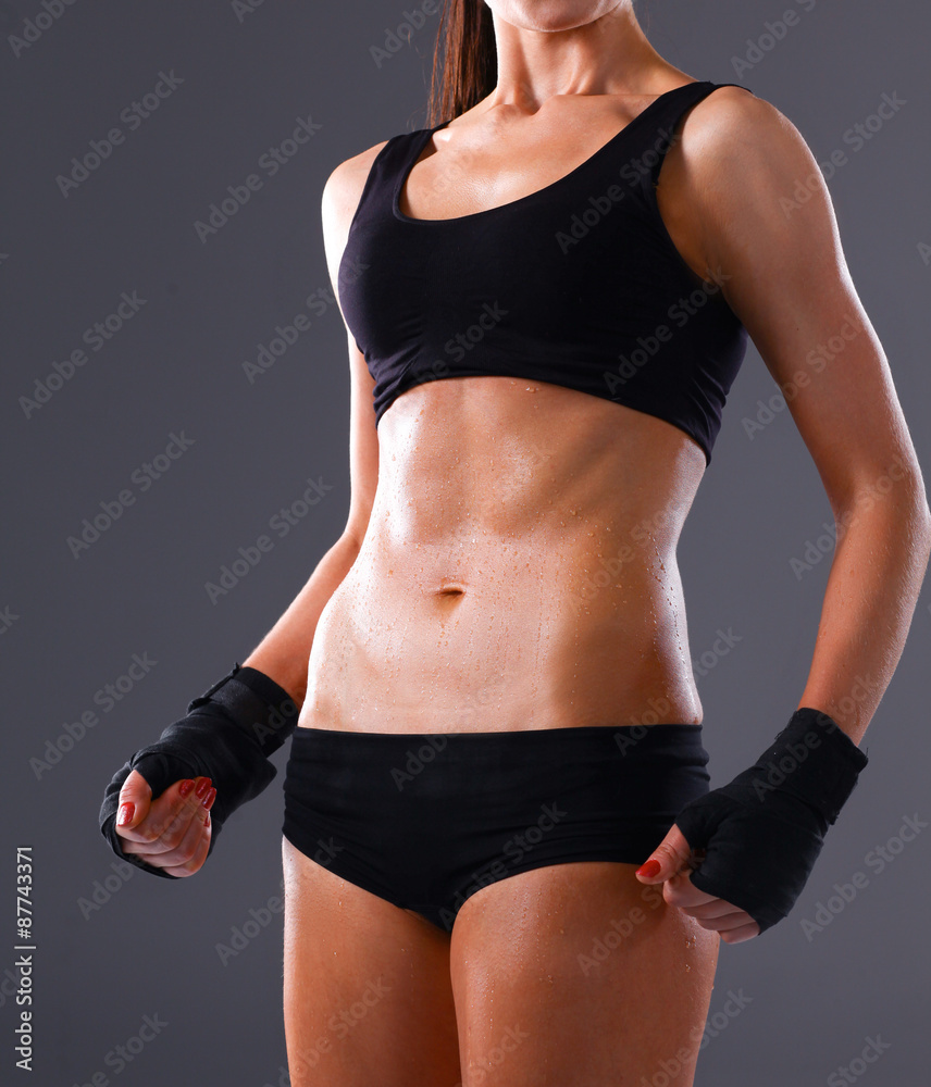 Muscular young woman standing on gray background Muscular young woman standing on gray background