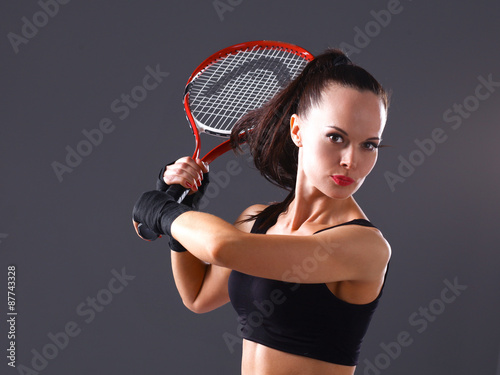 Woman playing tennis on gray background