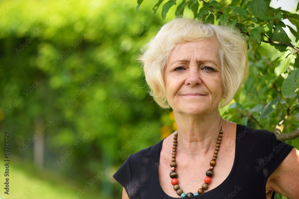 Mature, blonde woman in garden,