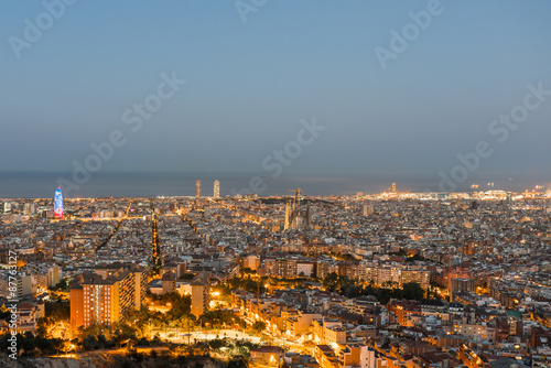 Top view and night photography of an illuminated Barcelona. The panorama shows the famous Sagrada Familia, the illuminated Torre Agbar and the Towers of the Port Olimpic until the harbor