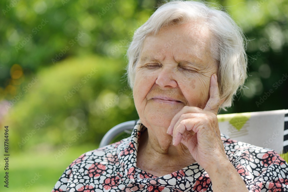 Senior woman smiling and dreaming in garden.